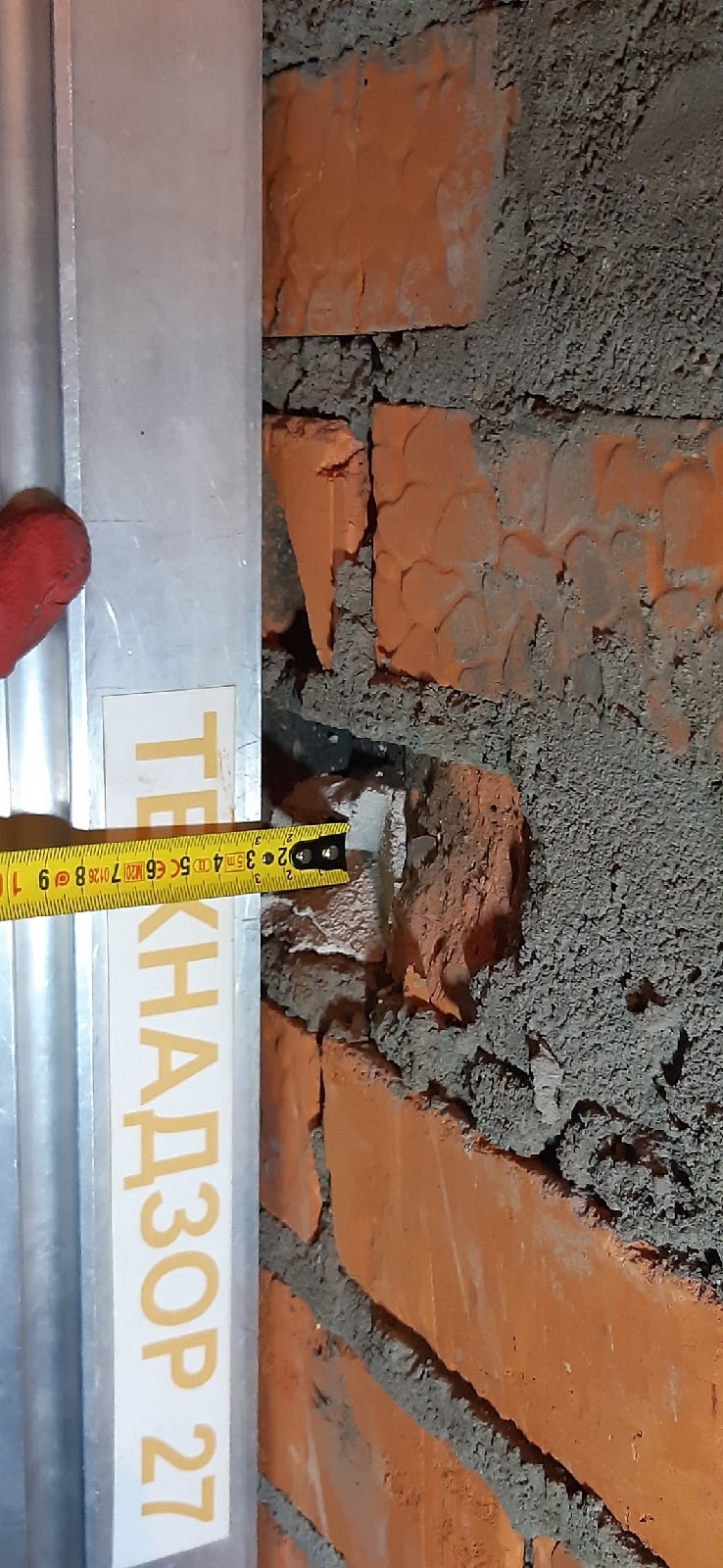 Пустые швы и повреждения кирпичной кладки рядом с металлическим ограждением при осмотре объекта